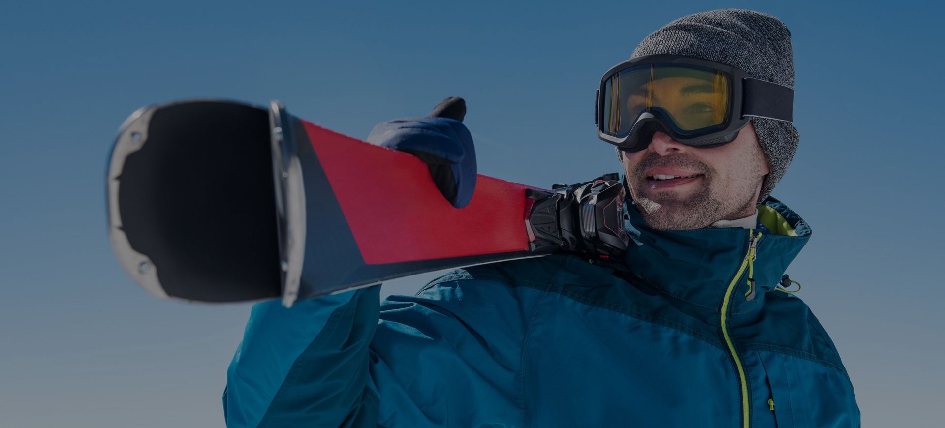 Sciatore felice con sci in spalla noleggiati da Deliv Rent